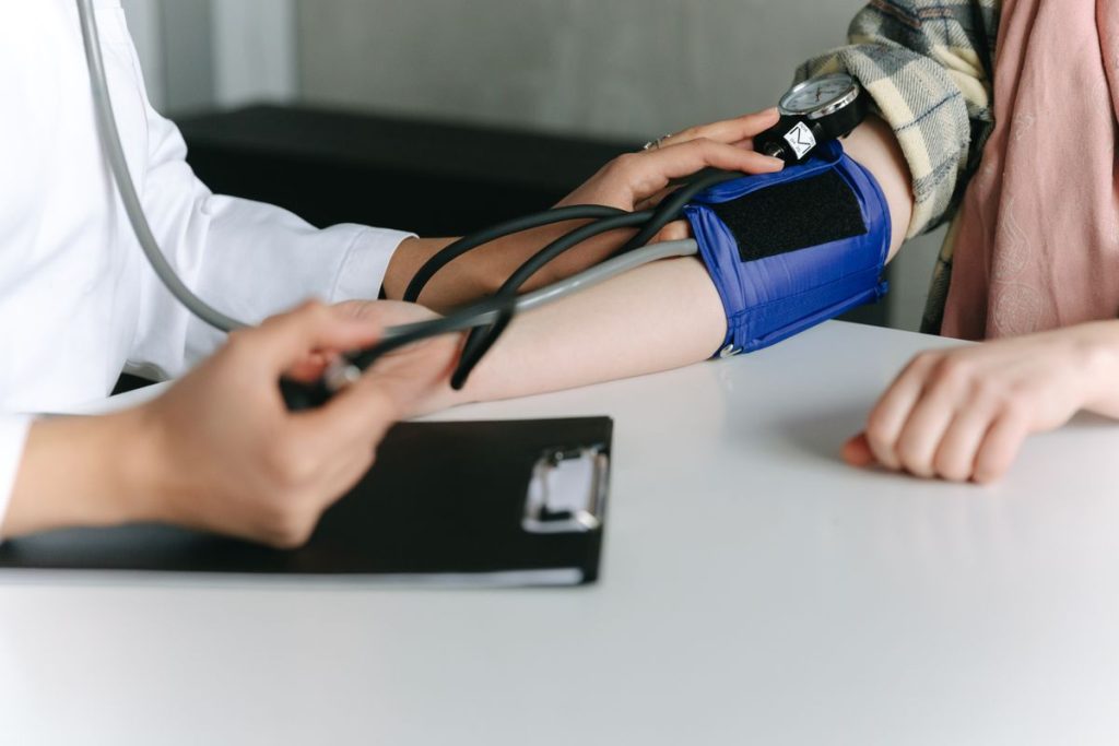 Healthcare worker checking a patient's blood pressure at a hypertension follow-up visit