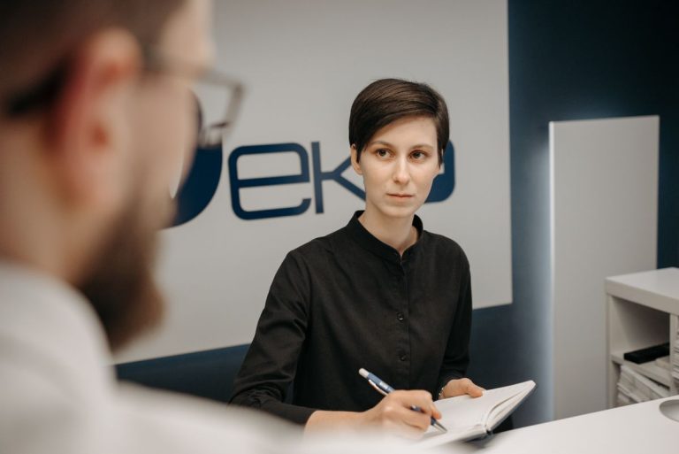 Clinic receptionist taking notes at the front desk during patient registration